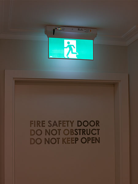 EMIoT LED Emergency Exit Sign infront of Fire Safety Door